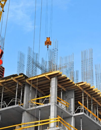 Construction site with crane and building framework against a blue sky.